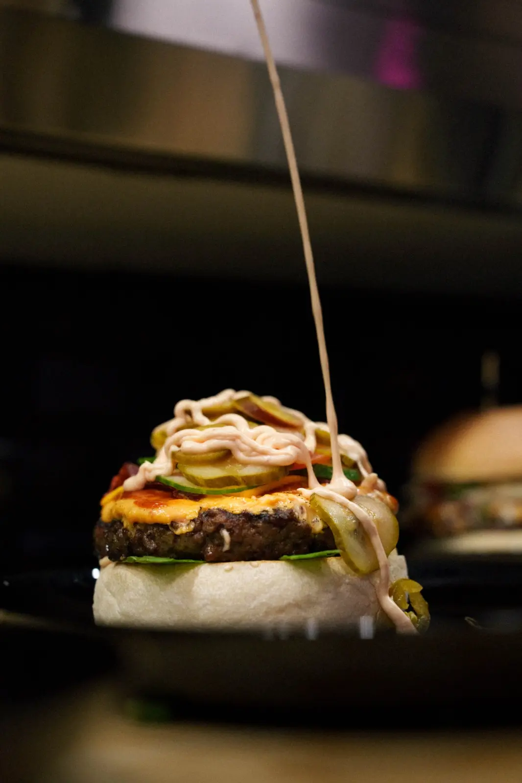 Burger wird mit Sauce fertiggestellt